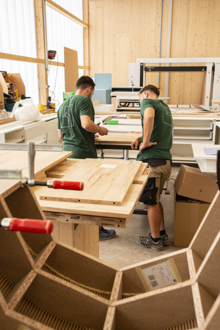 Zwei Mitarbeiter der Schreinerei Huber in der Werkstatt besprechen den nächsten Schritt in der Fertigung.