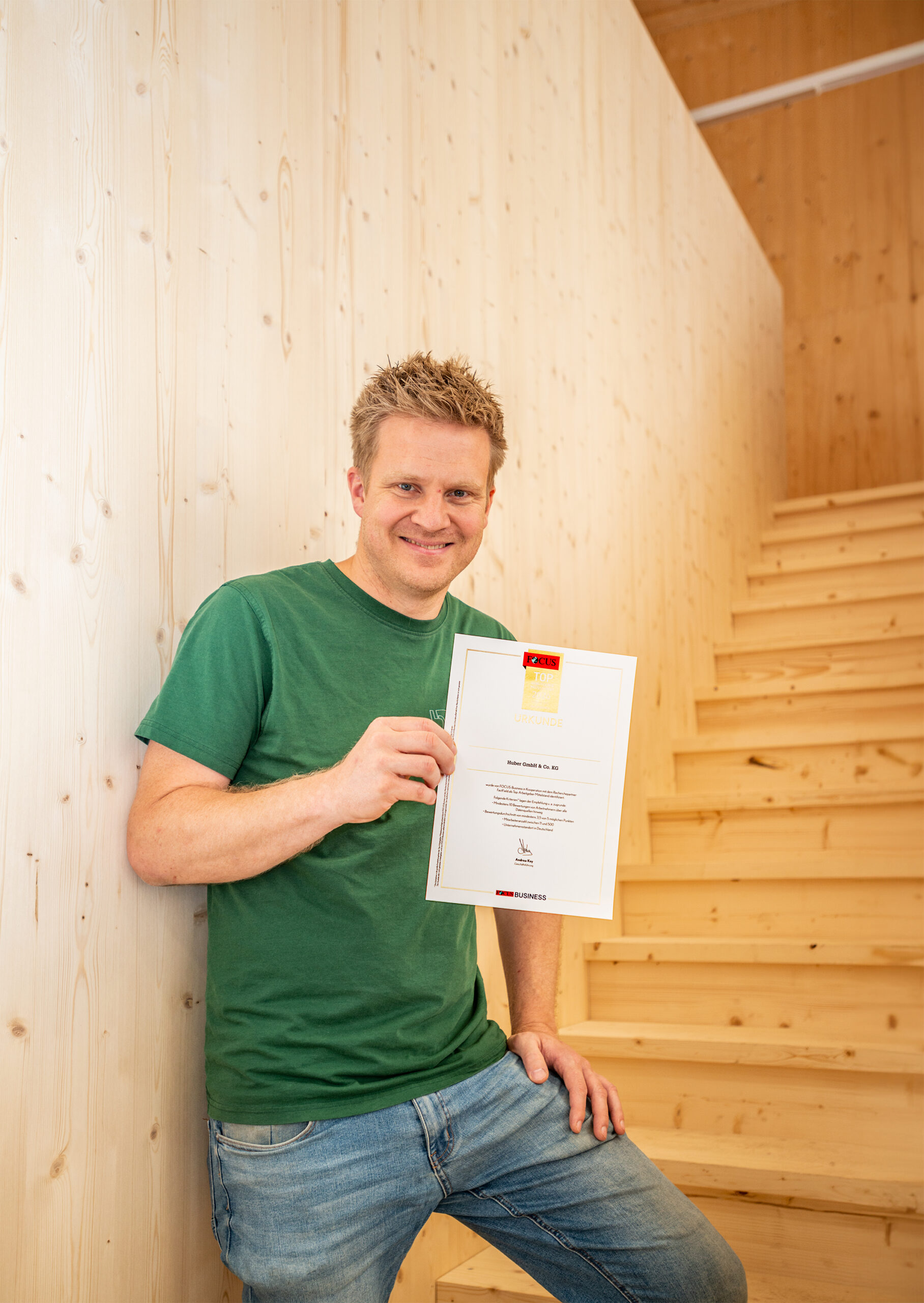 Dominic Huber zeigt die Auszeichnung vom Magazin Focus zum TOP-Arbeitgeber