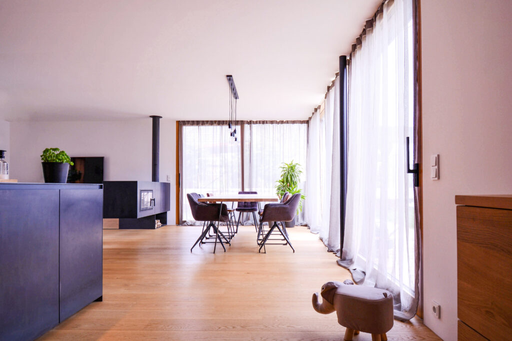 Individueller Innenausbau im Wohnzimmer mit Echtholzmöbeln und großen Fensterfronten.